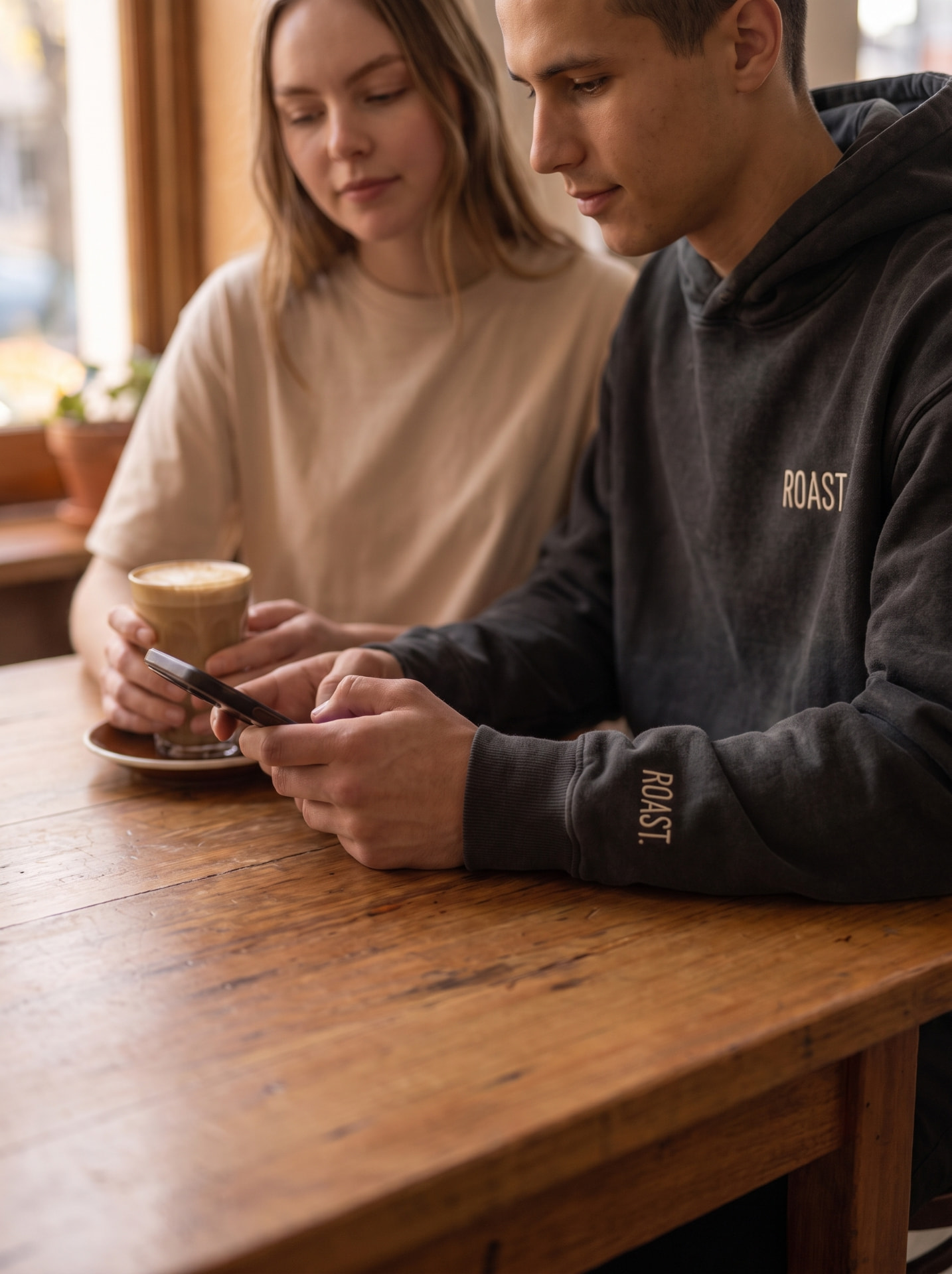 ROAST hoodie at the café table with a flat white
