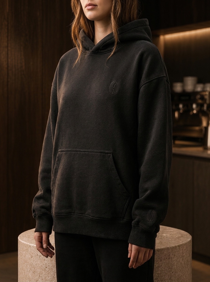 Frau trägt den washed black ROAST Hoodie im Café